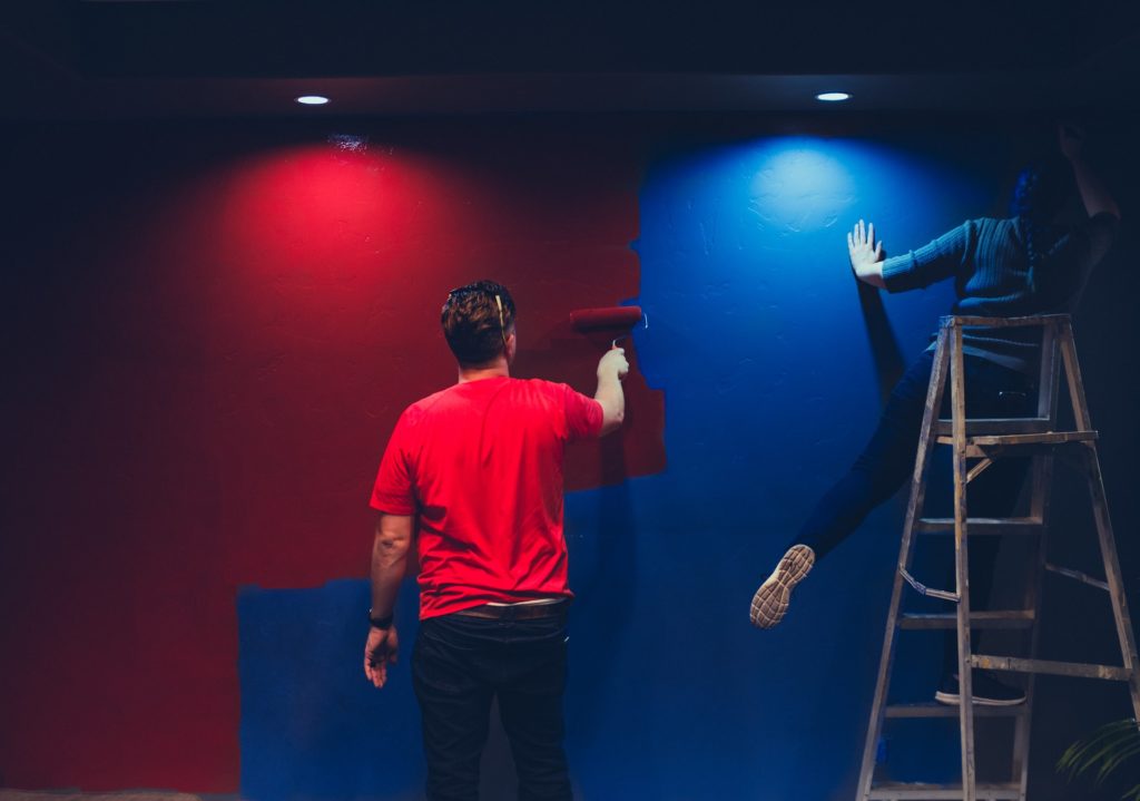 Two people applying different types of wall paint and finishes