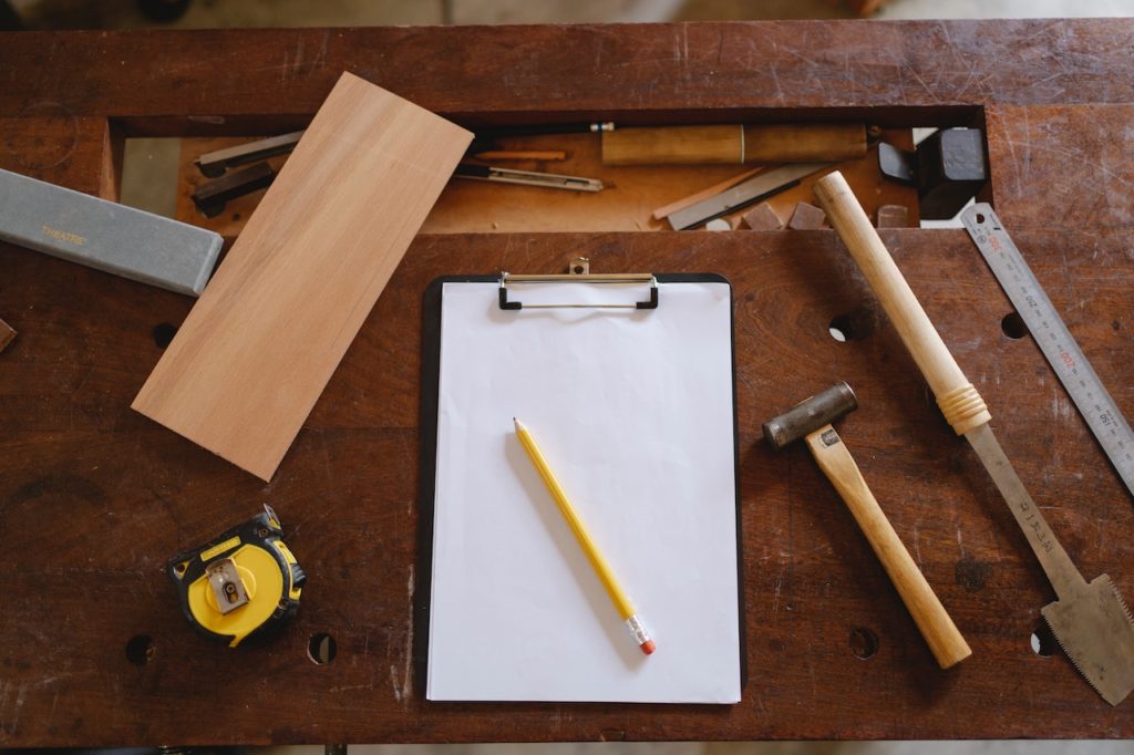 Carpentry tools arranged around a piece of paper and a yellow pen.